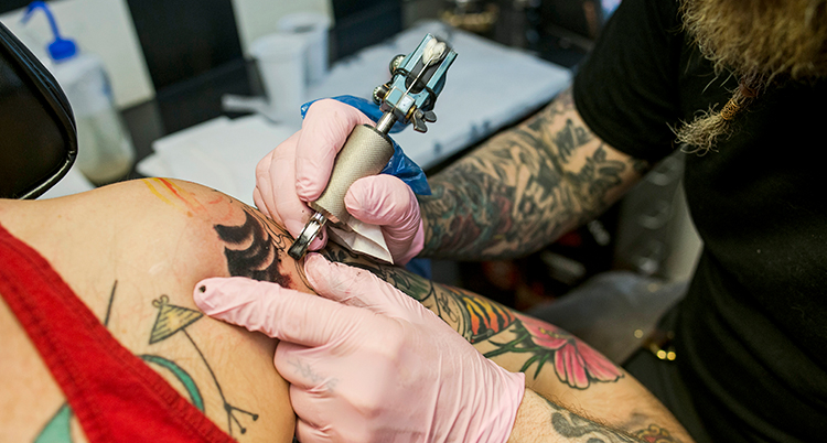 En person håller i maskinen med nålen som tatuerar.