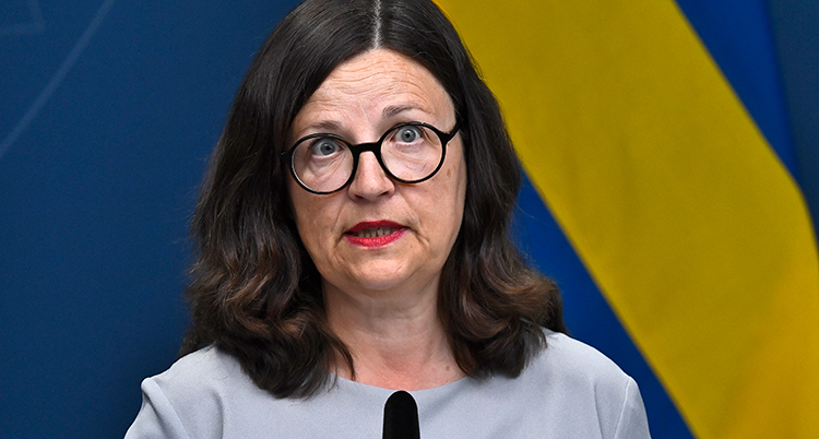 Anna Ekström framför en blågul vägg på en presskonferens.