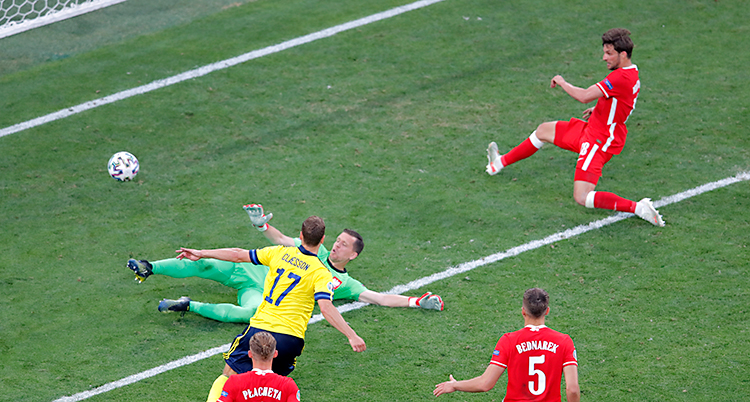 Från en match i fotboll. Viktor Claesson sparkar bollen mot mål. Polska spelare försöker stoppa honom.
