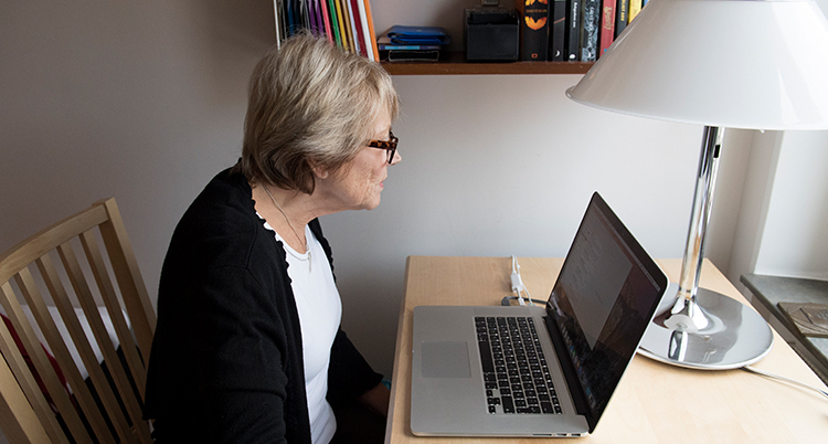 En kvinna sitter framför en dator. Hon tittar på skärmen.