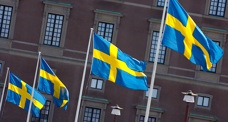 Fyra svenska flaggor på flaggstänger.