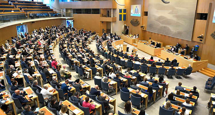En bild över riksdagens stora sal. Politiker sitter i alla bänkar.