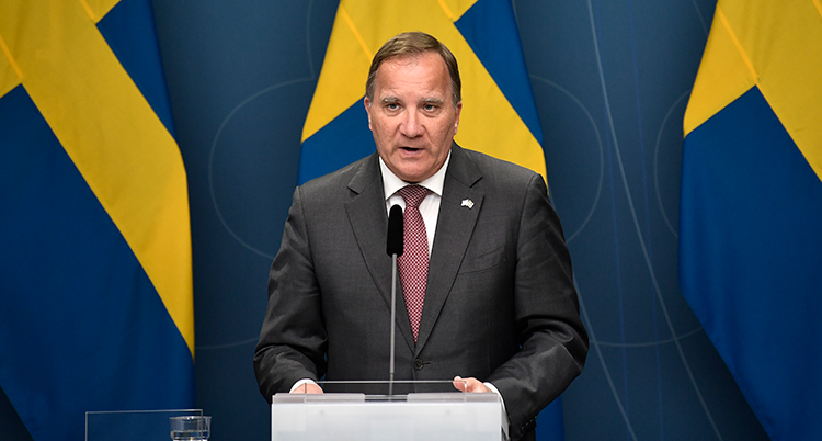 Löfven talar. Bakom honom är svenska flaggor.