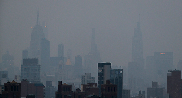 En bild som visar höga hus i staden New York. Luften är grå och disig. Det beror på rök från bränder.