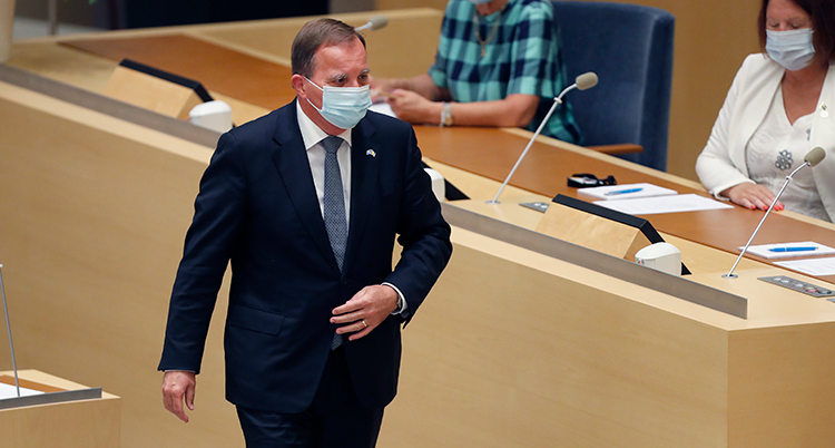 Stefan Löfven i munskydd går fram till talmannen efter omröstningen.