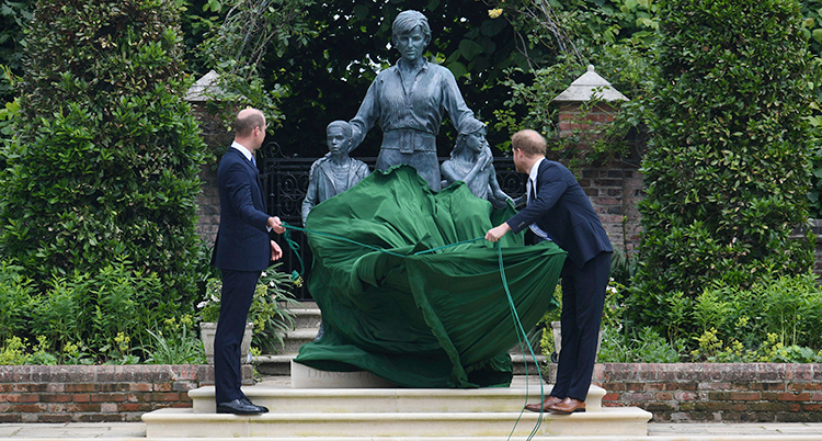 De drar i ett grönt skynke. Diana i sten står upp och håller om barn.