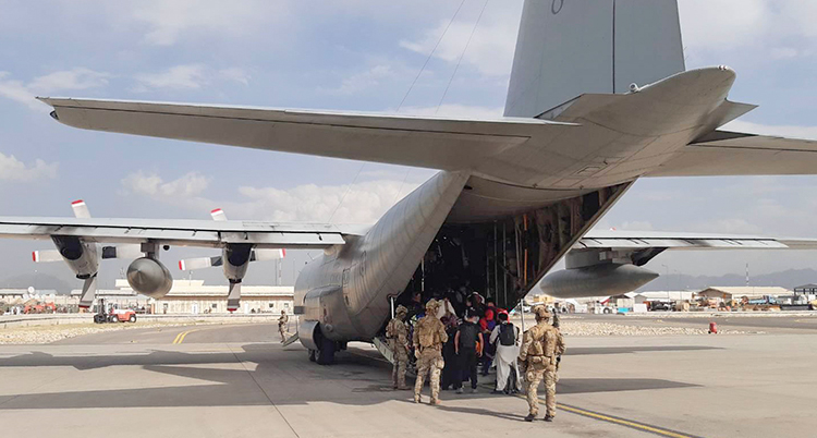 Ett militärflygplan som har en stor öppning längst bak i planet står på flygplatsen.