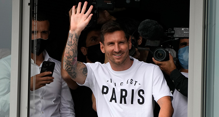 Messi ler och vinkar. Han har en tröja där det står Paris.