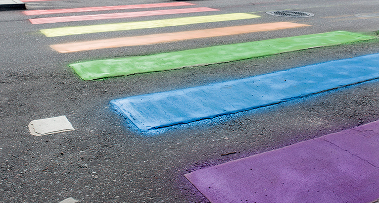 Ett övergångsställe på en asfaltsvägen där strecken har regnbågens färger