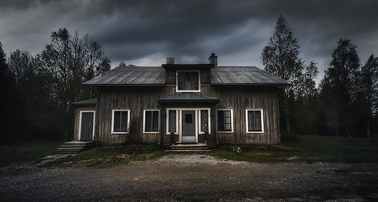 Ett grått hus med en mörk himmel ovanför.