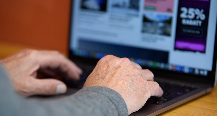 Händerna ligger mot tangenterna på en bärbar dator på ett bord