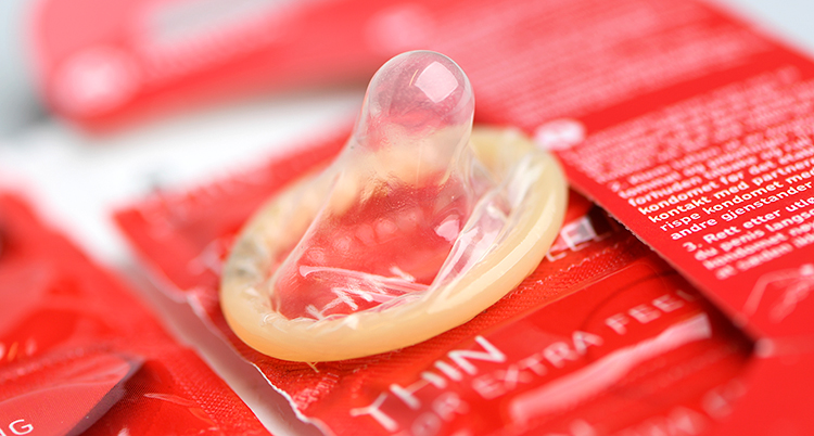 En hoprullad kondom ligger på en röd förpackning
