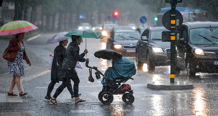 Människor går över en gata i kraftigt regn.