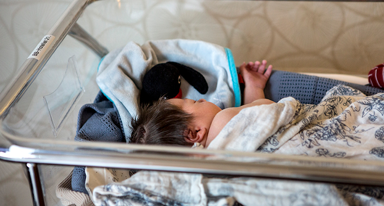 En nyfödd bebis ligger i en säng på ett sjukhus.