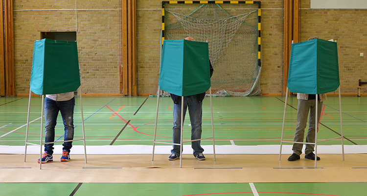 Tre personer bakom skärmar och röstar.
