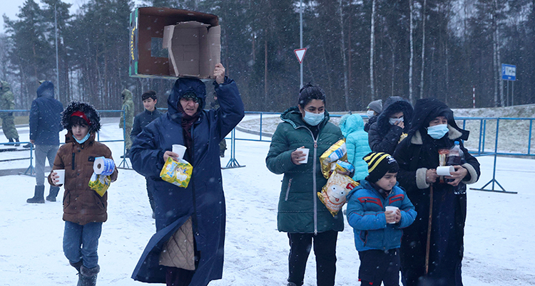 Flyktingar bär mat i Belarus nära gräsen till Polen.