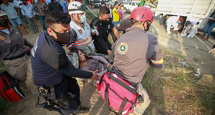 Fem personer som jobbar som räddningspersonal bär tillsammans en kvinna som är skadad.