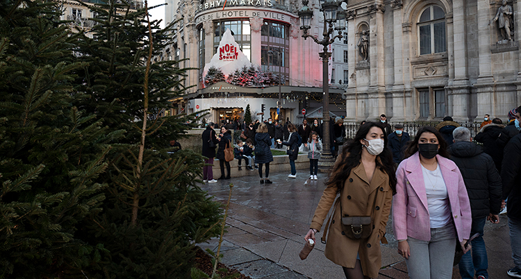 Människor rör sig på ett torg i Paris. Två kvinnor med munskydd är närmast kameran.