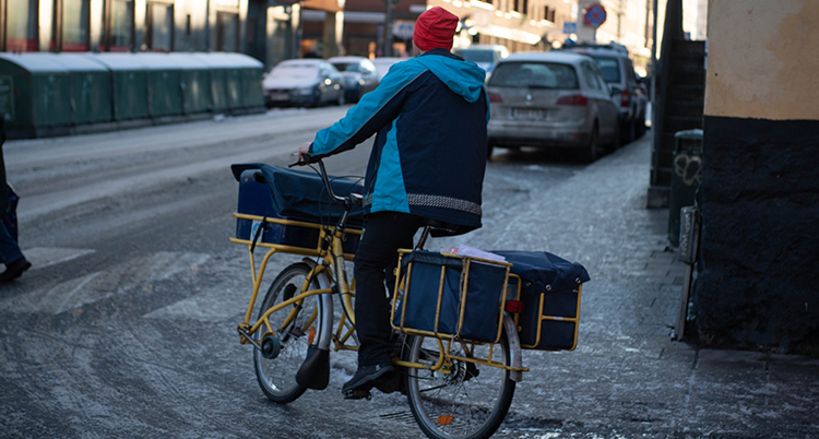 En brevbärare cyklar med en postcykel