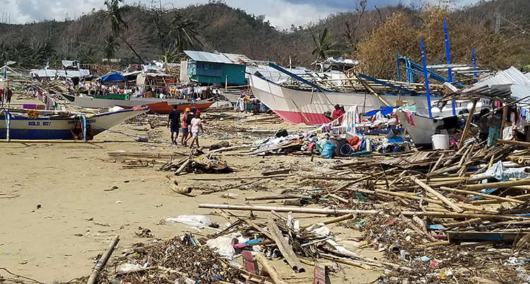 En strand med bråte och förstörda stora båtar.