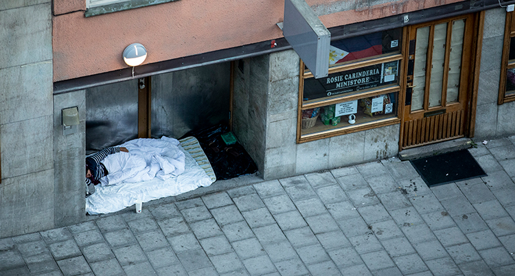 En hemlös person sover i en port vid ett hus med lägenheter.