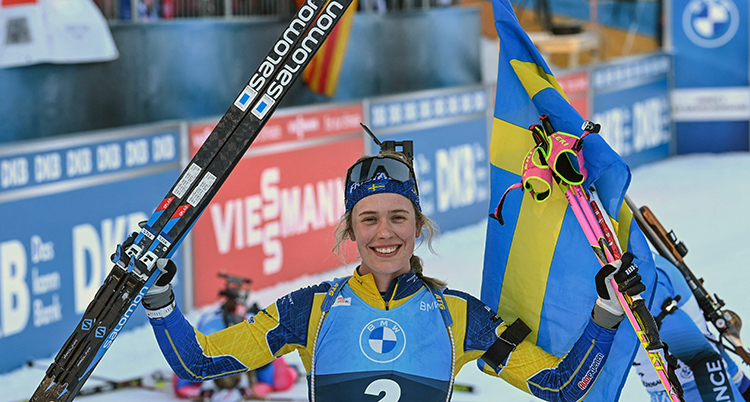 Öberg håller upp en flagga och sina skidor.
