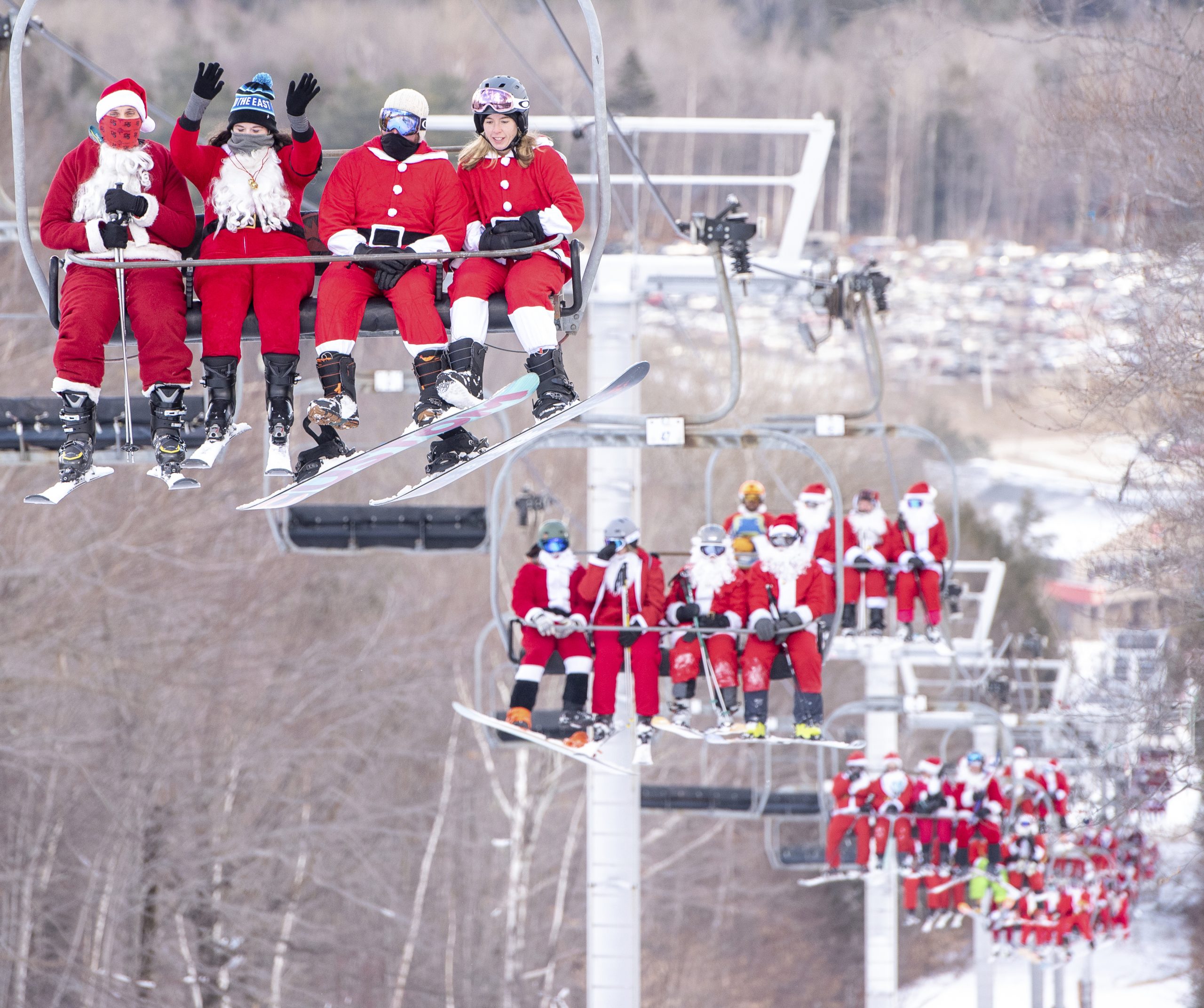 Röda jultomtar sitter i liftar i luften.