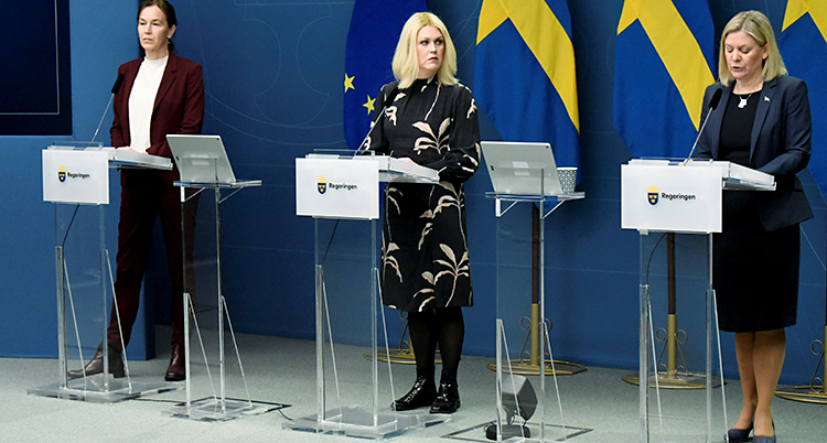 Tre kvinnor står bredvid varandra och har en presskonferens.