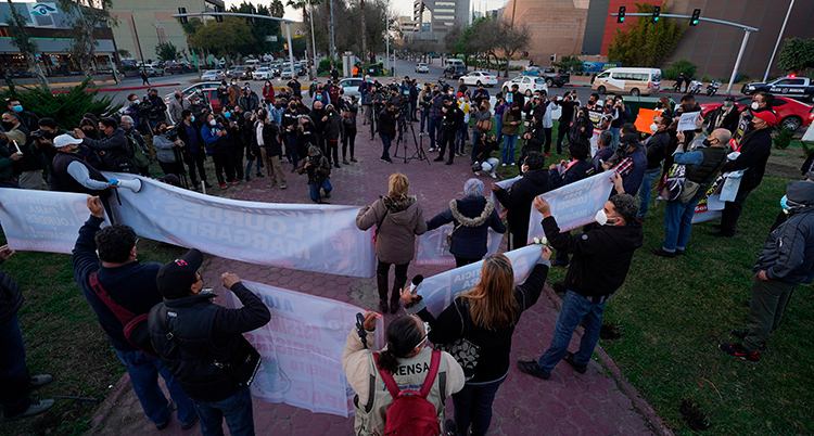 En grupp människor är samlade på en öppen yta, vissa håller banderoller.