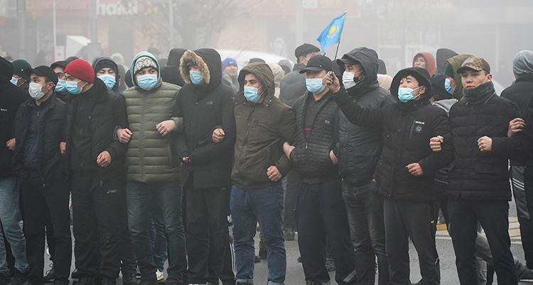 Demonstranter i Kazakstan håller om varandra.