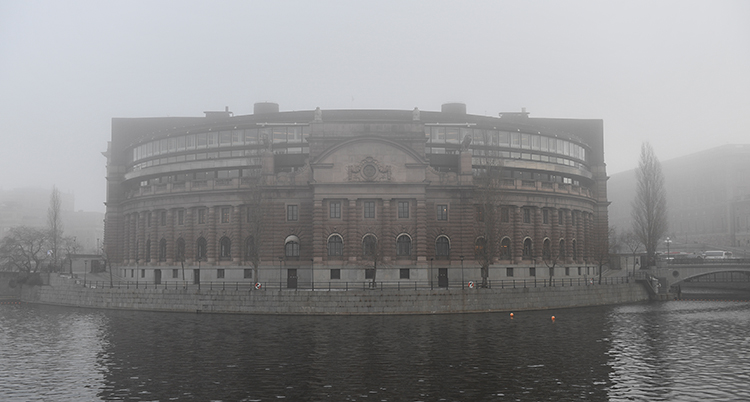 En bild som visar utsidan av riksdagens hus, på en dimmig dag.