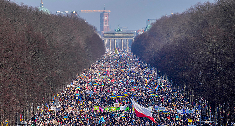 Det är fullt med folk på en stor gata i Berlin.