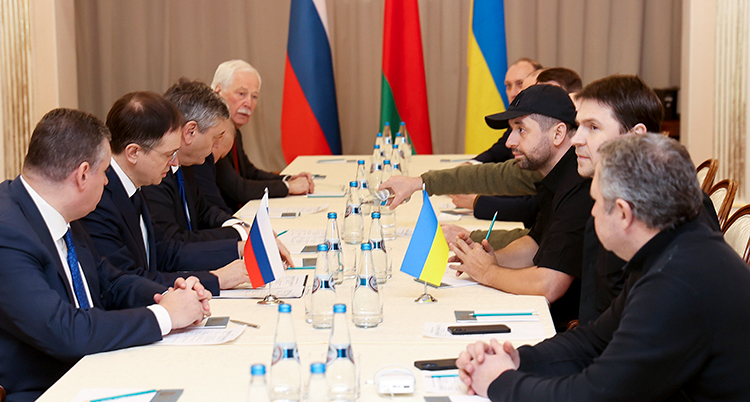 fyra män på vänstra sidan och fyra män på högra sidan vid ett långbord. Bakom kortsidan av bordet står tre flaggor, Rysslands, Ukrainas och Belarus.