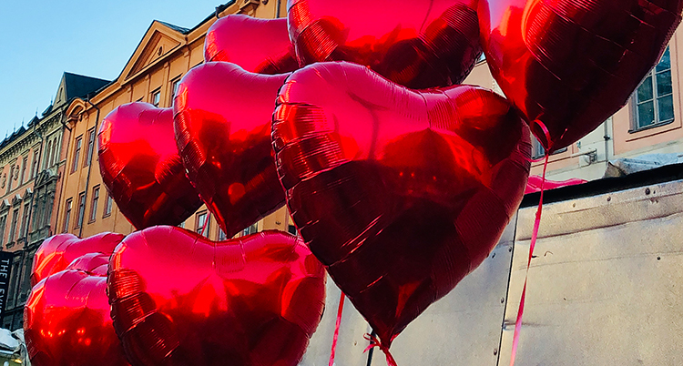 Ballonger i form av hjärtan syns i luften framför ett hus