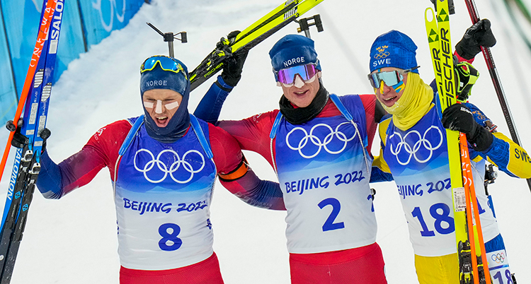 Tre åkare ler och håller uppp sina skidor.