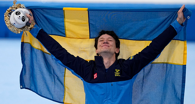 Nils sträcker upp en svensk flagga bakom sig och tittar upp i taket.