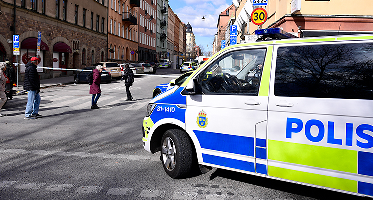 En gata i Stockholm. Poliserna har spärrat av med band. Flera polisbilar är där.