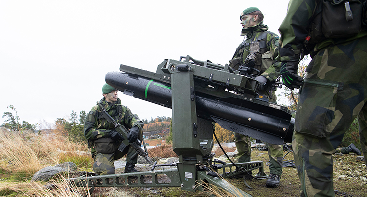 Soldater i gröna militärkläder övar vid en modern kanon.