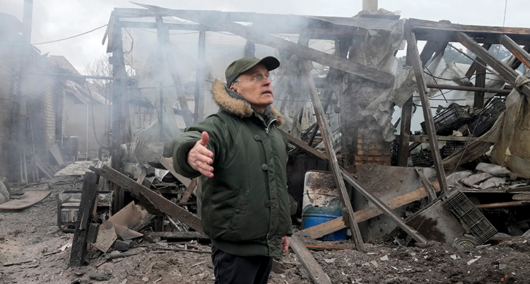 En man står vid sitt bombade hus.