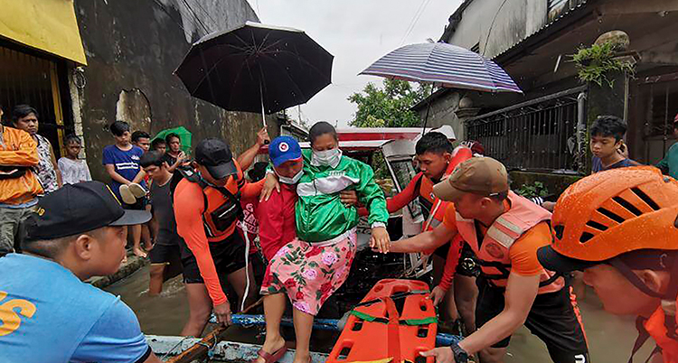 Människor hjälper en kvinna i Filippinerna. Det har varit en svår storm där.