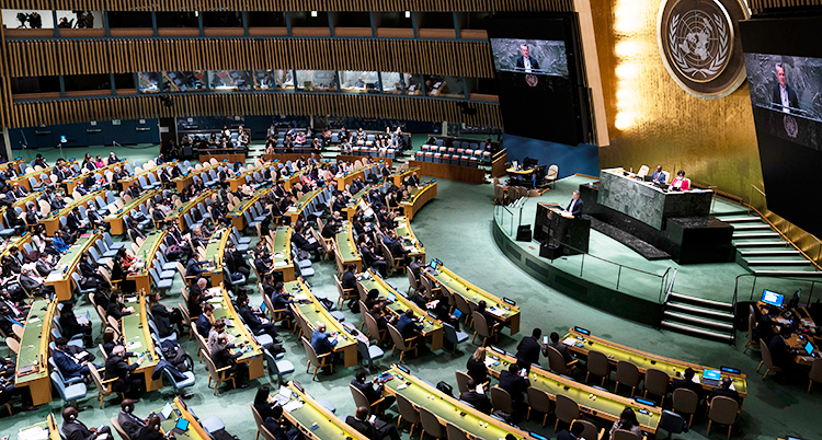 FN stora sal med många människor som sitter vid bänkar vända mot ett podium.