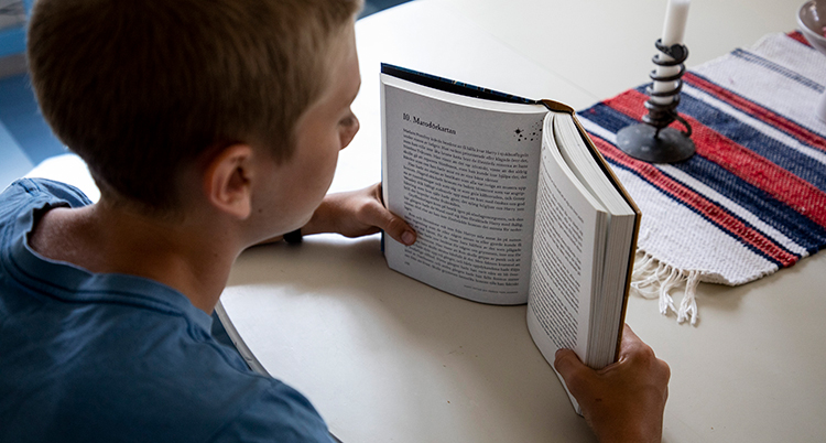 Ett barn sitter vid ett bord och håller i en bok.