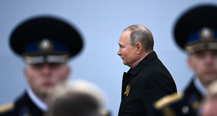 Rysslands president Vladimir Putin går bakom två militärer.