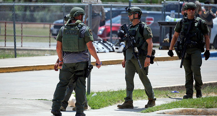 Män med uniform och vapen utanför skolan.