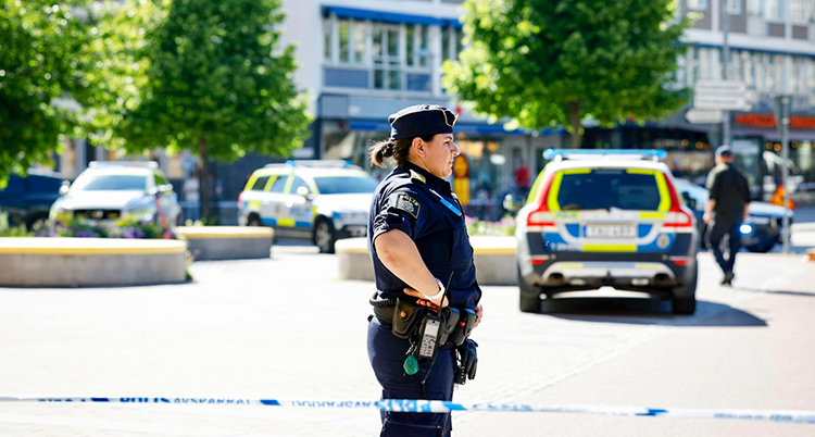 en polis vaktar framför en avspärrning med ett band på en gata i Västerås.