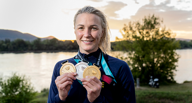 Kvinna visar upp sina medaljer från VM i simning.