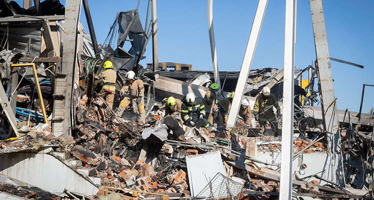 Räddningsarbetare står i massorna av ett rasat hus
