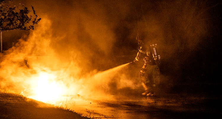 En brandman jobbar med att släcka en brand i mörkret.