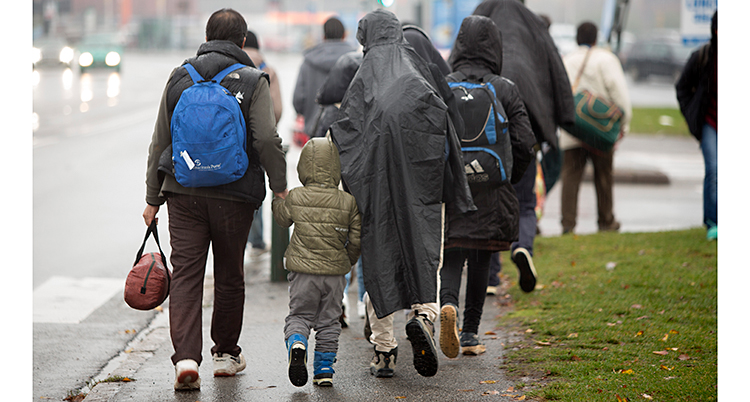 Några flyktingar går på en gata i Malmö. Vi ser dem bakifrån.