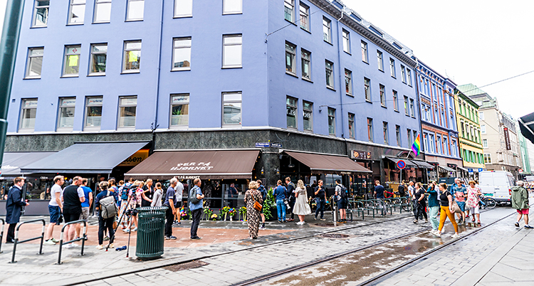 En gata mitt i Oslo med ett blått hus med barer på gatuplan.